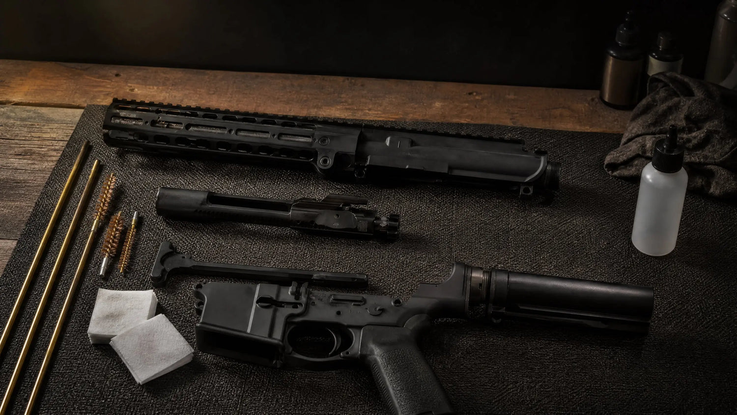 AR-15 rifle field-stripped on dark gun cleaning mat with cleaning tools, best ar-15 cleaning kit